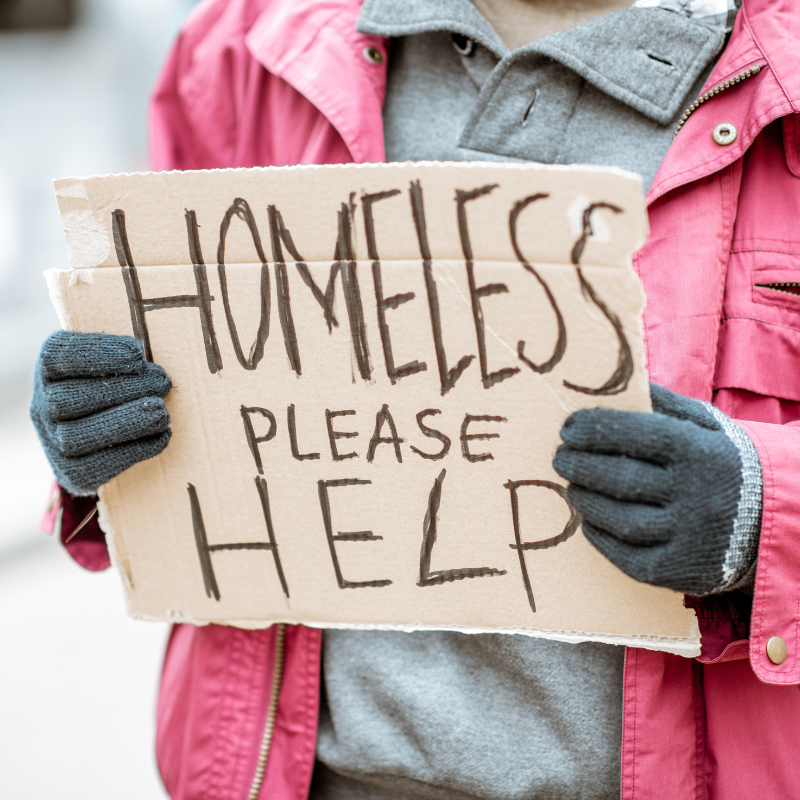 Person holding a sign stating 'homeless please help'